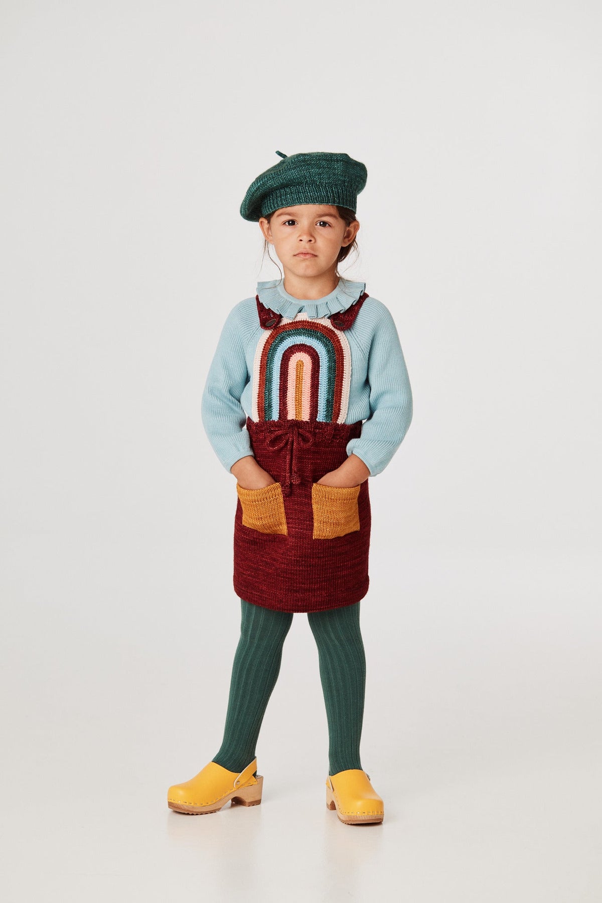 Rainbow Pinafore - Cranberry+Model is 42 inches tall, 40lbs, wearing a size 3-4y