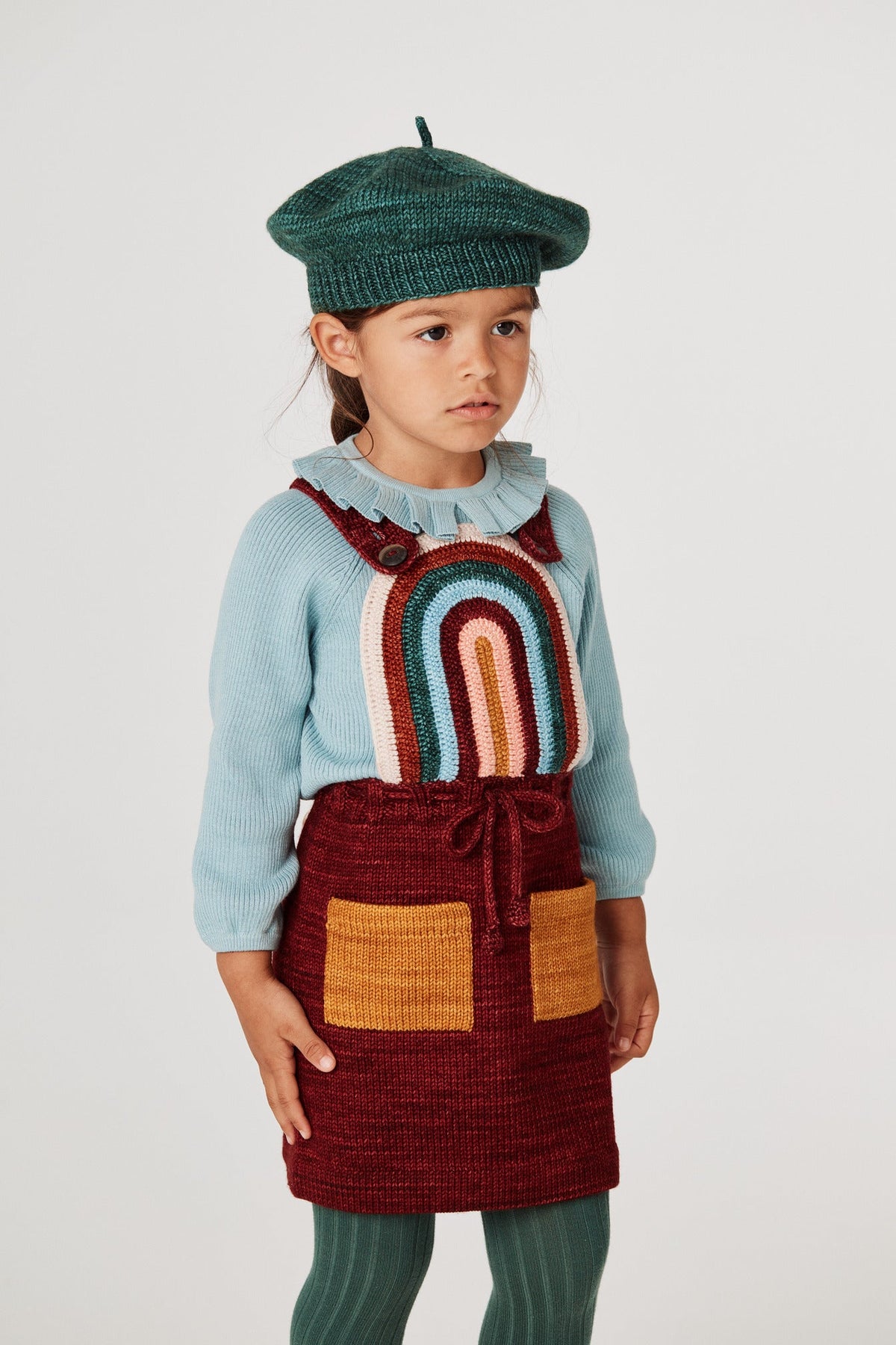 Rainbow Pinafore - Cranberry+Model is 42 inches tall, 40lbs, wearing a size 3-4y